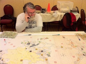 Andrew Nisbet surveys an Empire map and pieces being set up to play Tac 5 (March 2011 at the GameStorm convention in Vancouver, WA)